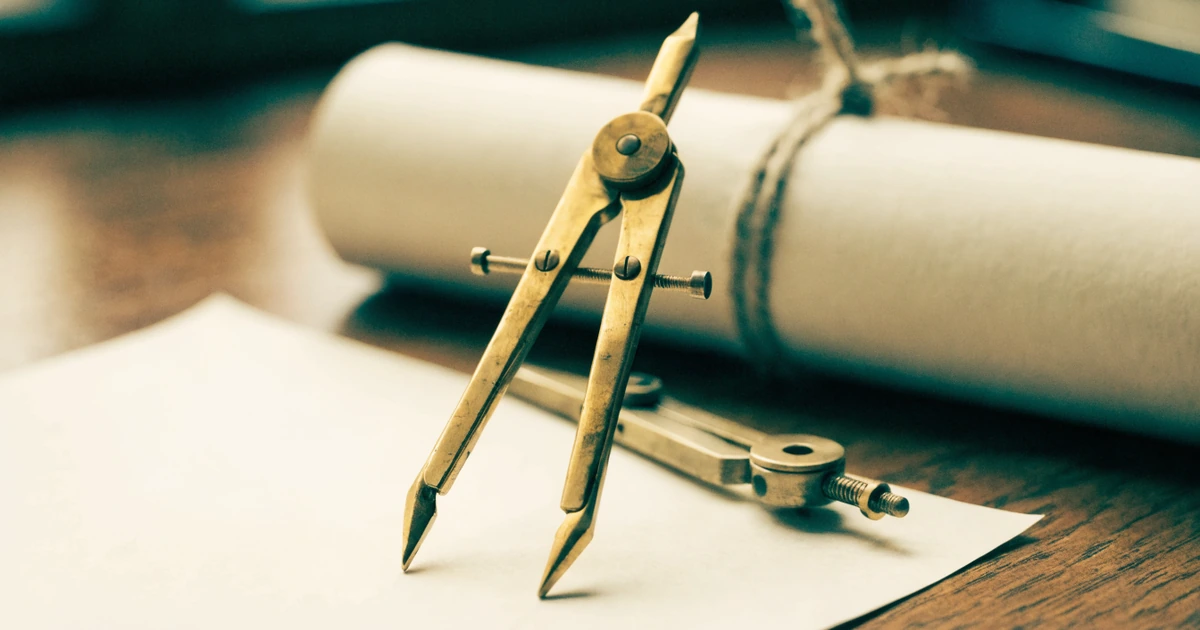 A pair of antique brass drawing dividers resting on a plain sheet of paper beside a tied paper scroll