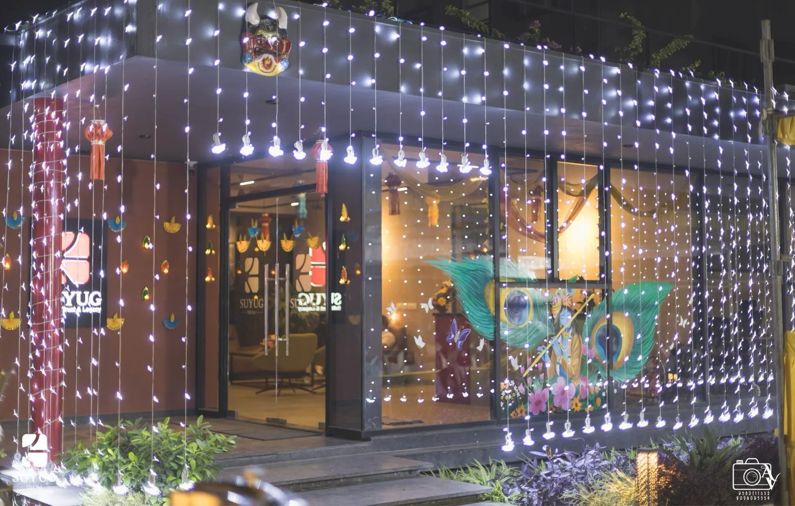The office frontage under curtain lights, paper diyas strung across the glass and painted panels lit from within.