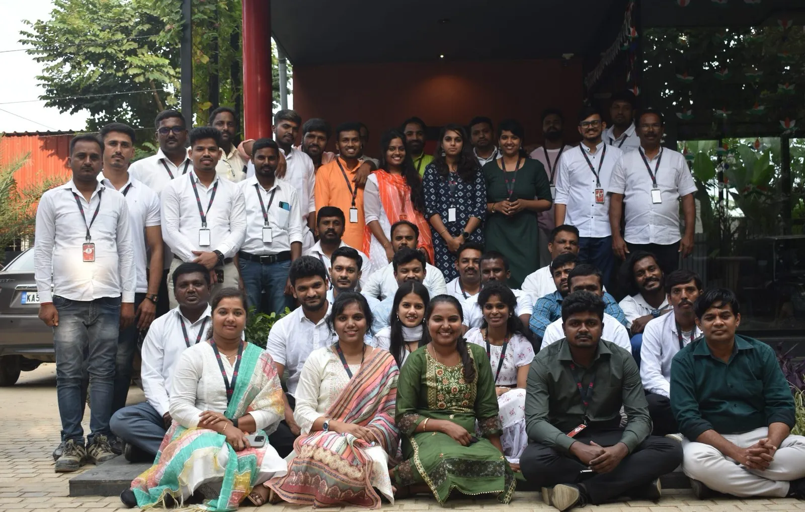 The team assembled outside the office in rows, most of them in white, for the group photograph.