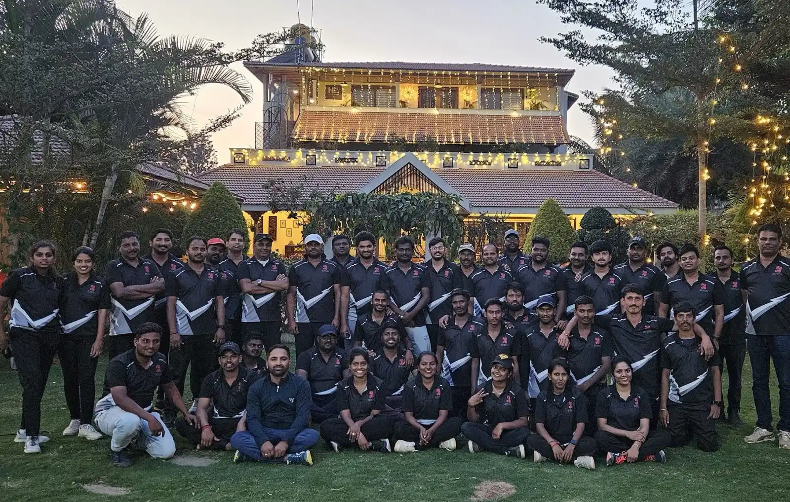 The whole team in matching jerseys at dusk, the lit resort building behind them.