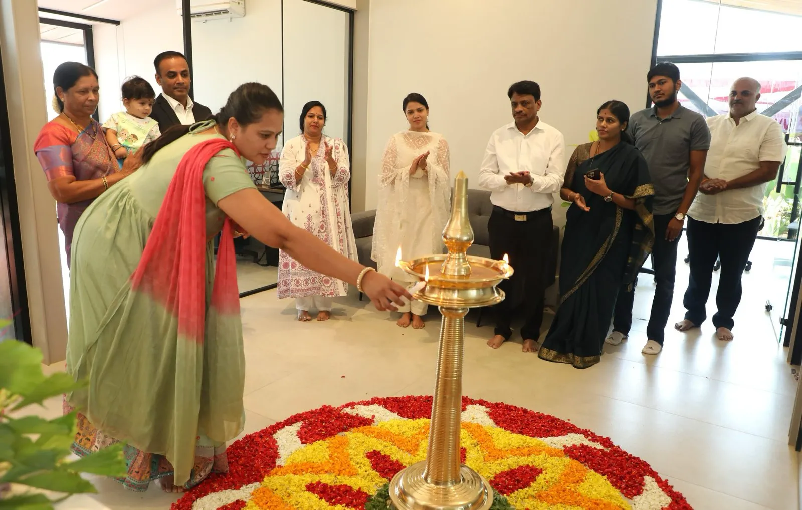 The lamp lit over a floral rangoli as the room applauds.