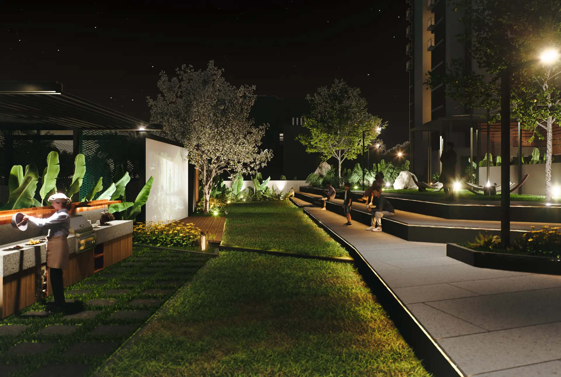 Night view of the open-air amphitheatre steps and barbecue counter, with an outdoor screening wall and lawn alongside the tower
